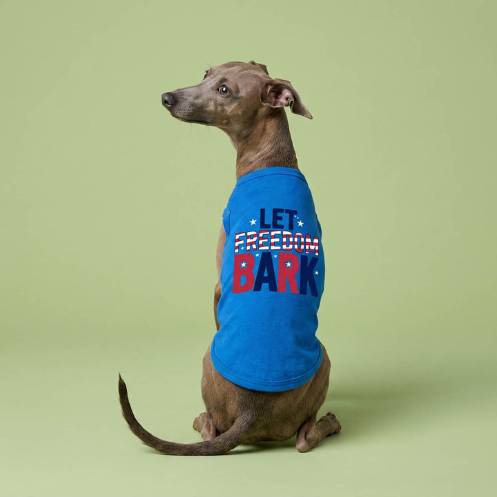 Back view of dog wearing a blue dog t shirt with 'Let Freedom Bark' lettering on a green background