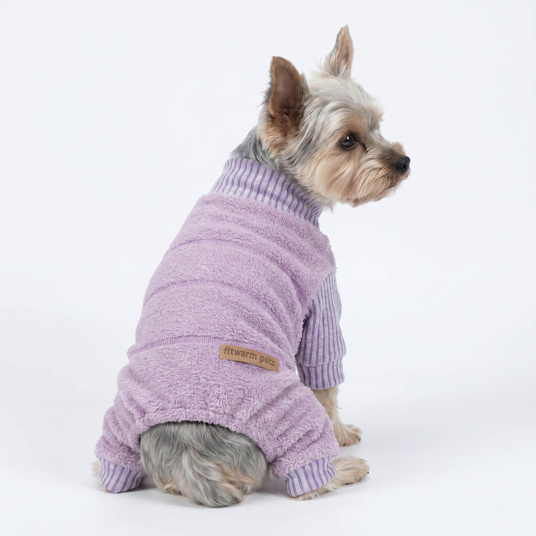 Yorkshire Terrier dog wearing a lavender dog fleece pajamas with purple striped sleeves, shown from the side against a plain white studio background