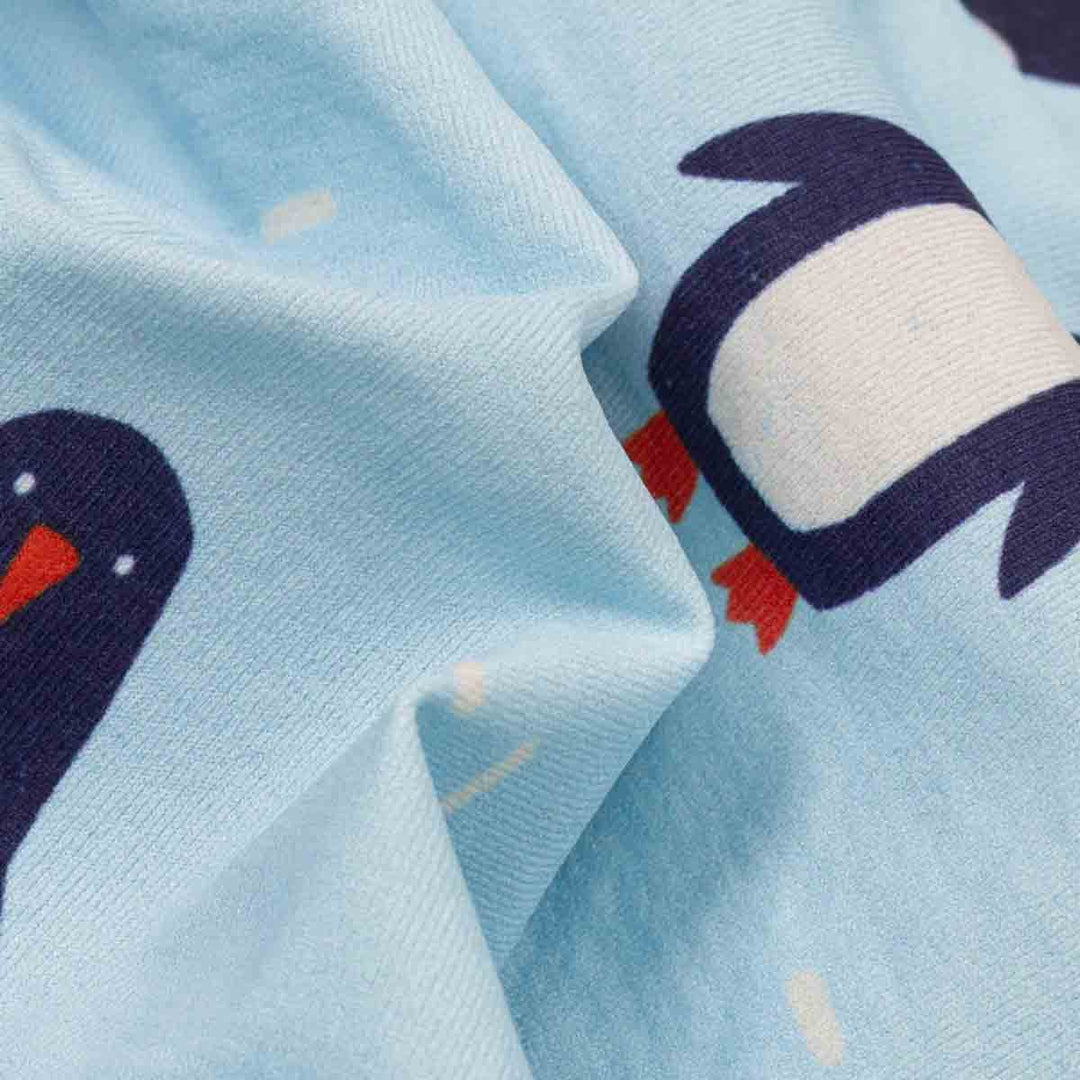 Cose-up of light blue fabric printed with cartoon penguin faces