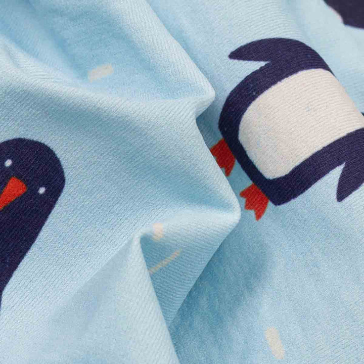 Cose-up of light blue fabric printed with cartoon penguin faces