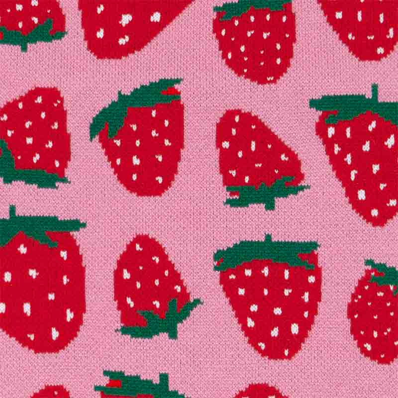 Flat-lay image of pink dog sweater with vivid red strawberry pattern.