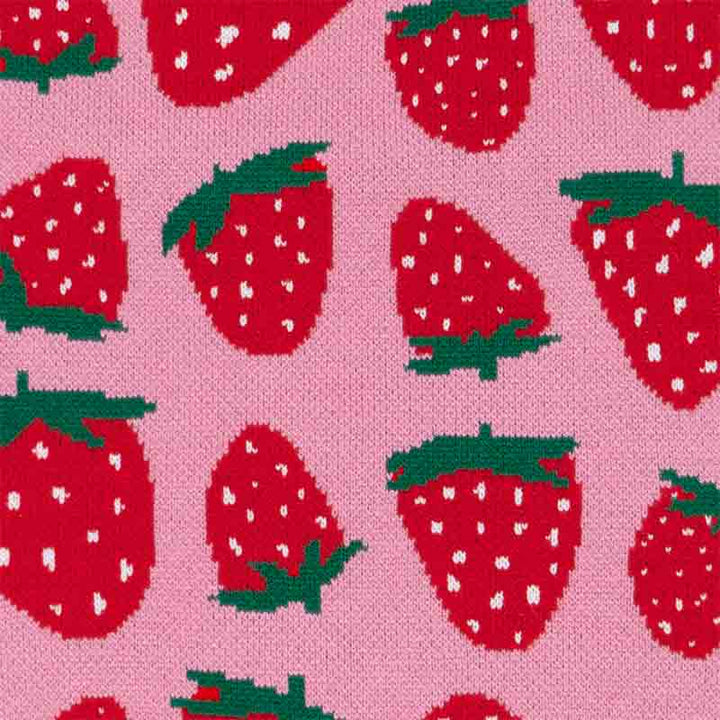 Flat-lay image of pink dog sweater with vivid red strawberry pattern.