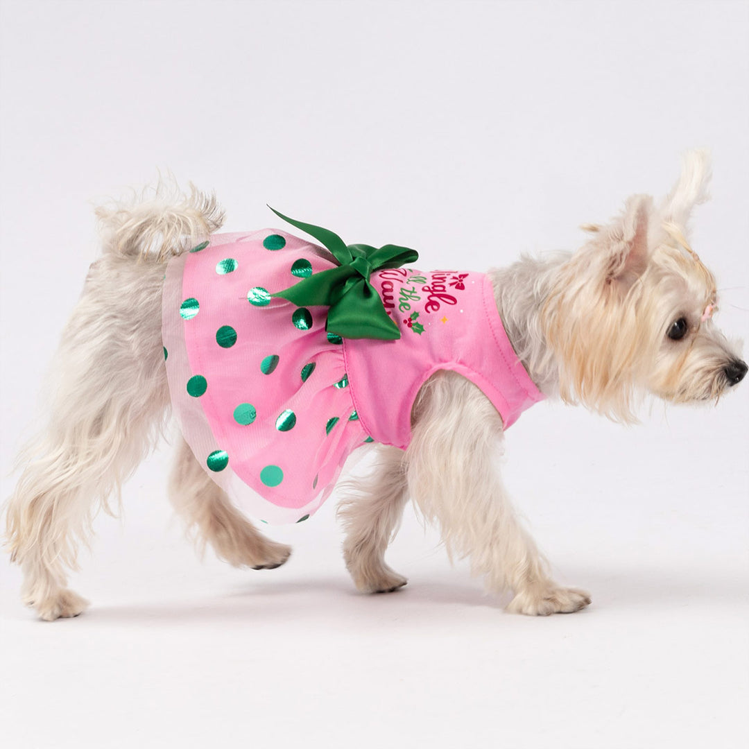 Cute dog dressed in festive pink Christmas dog dress featuring metallic green dots and a ribbon bow