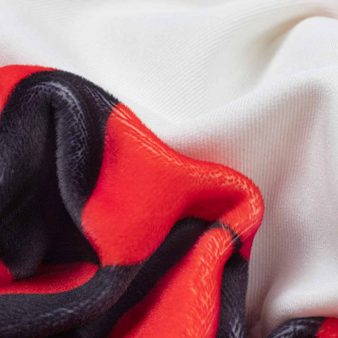 Close-up of a soft fabric with a bold red and black harlequin pattern
