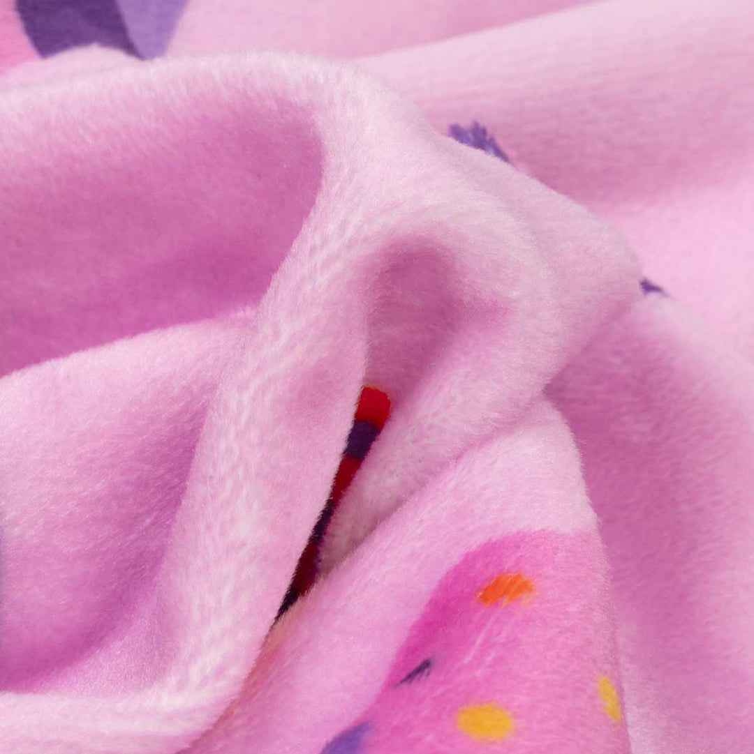 Close-up of soft pink fabric with a small cup cake patterned section showing red, yellow, and purple details