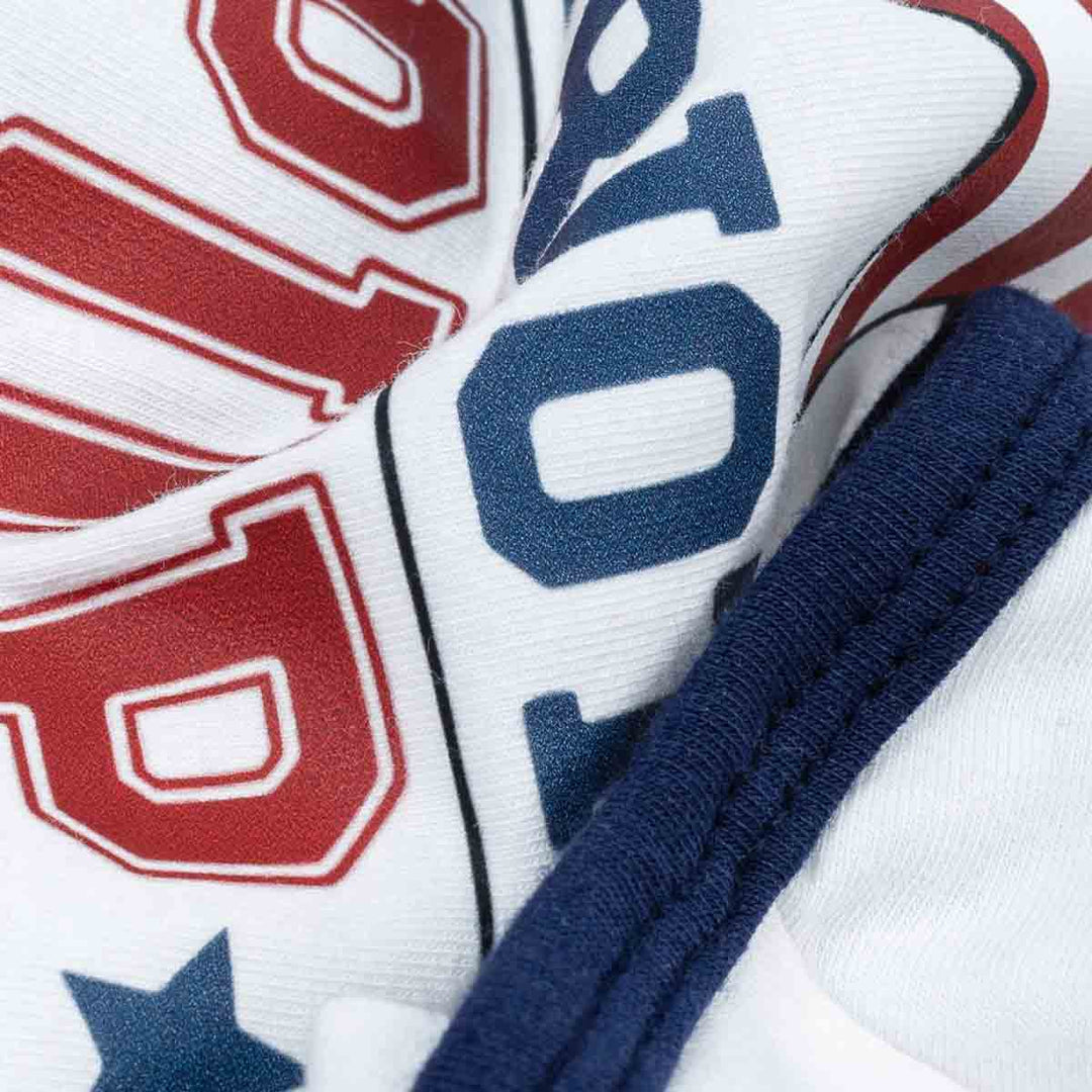 Close-up of Patriotic Pup dog shirt showing 'All American' lettering in red and blue on white fabric with blue trim.