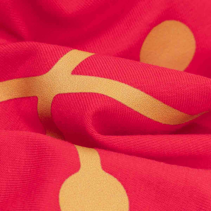 Close-up of bright red fabric with a large gold abstract wavy pattern and circular motifs