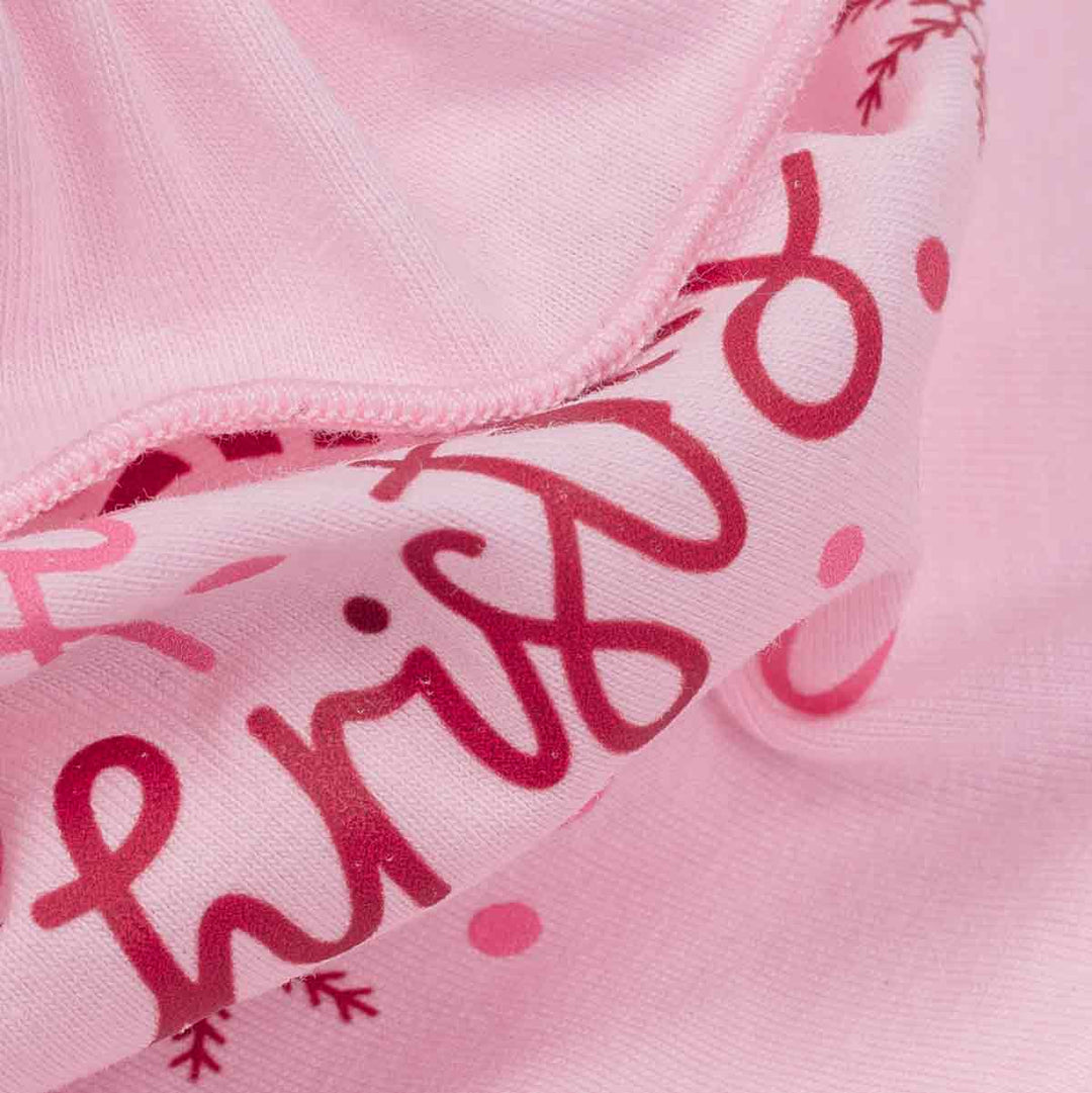 Close-up of a light pink fabric garment with dark red script lettering and small pink polka dots