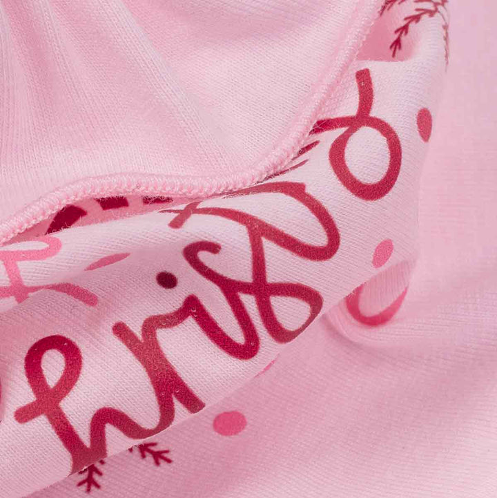 Close-up of a light pink fabric garment with dark red script lettering and small pink polka dots