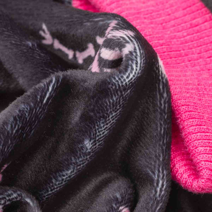 Close-up of a black plush dog fleece pajamas with a subtle white pattern, layered over a bright pink ribbed knit fabric
