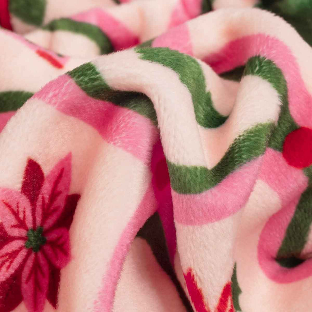 Close-up of a plush dog fleece pajamas with a pink and white chevron pattern, green accents, and red poinsettia flowers