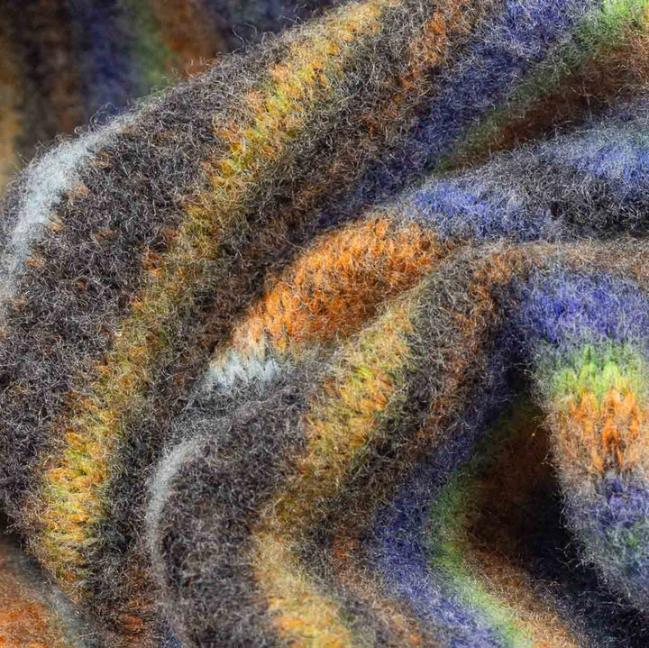 Close-up of a fuzzy, textured knit fabric with variegated stripes of gray, orange, purple, green, and cream