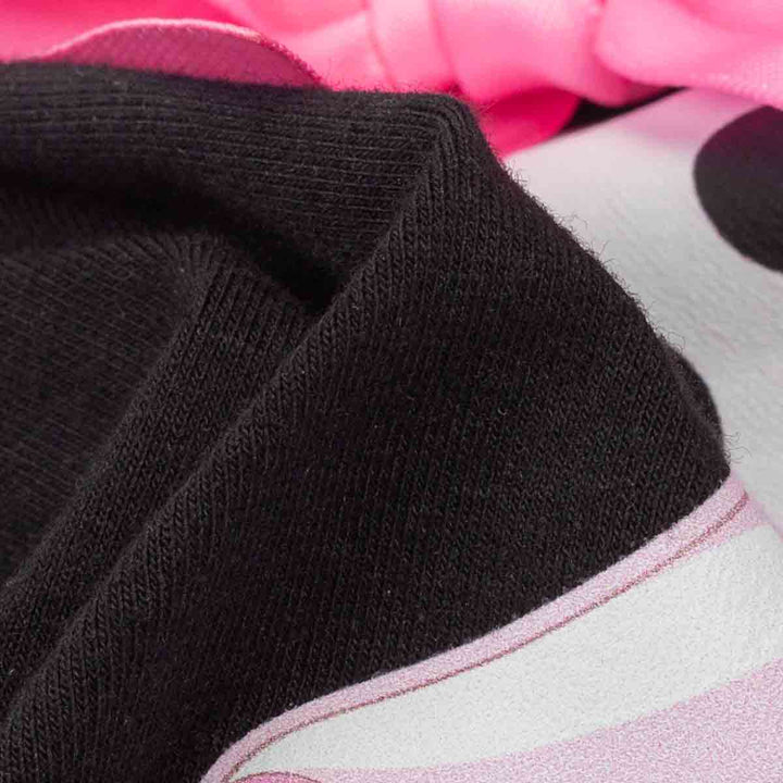 Close-up of a black ribbed knit fabric draped over a white and pink patterned textile with a pink bow at the top