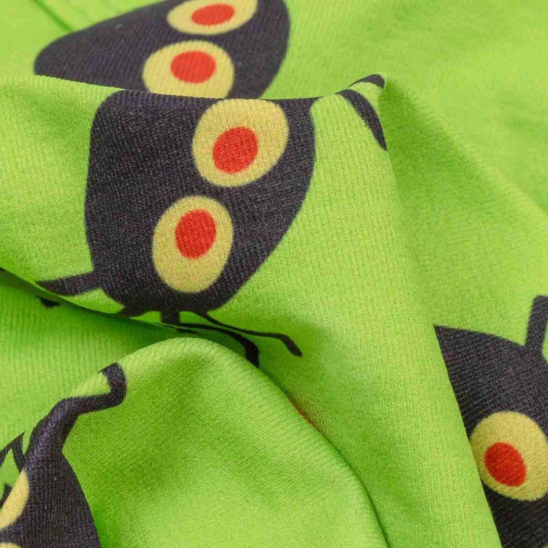 Bright lime green fabric with a repeating cartoon spider print, shown in a close-up draped view
