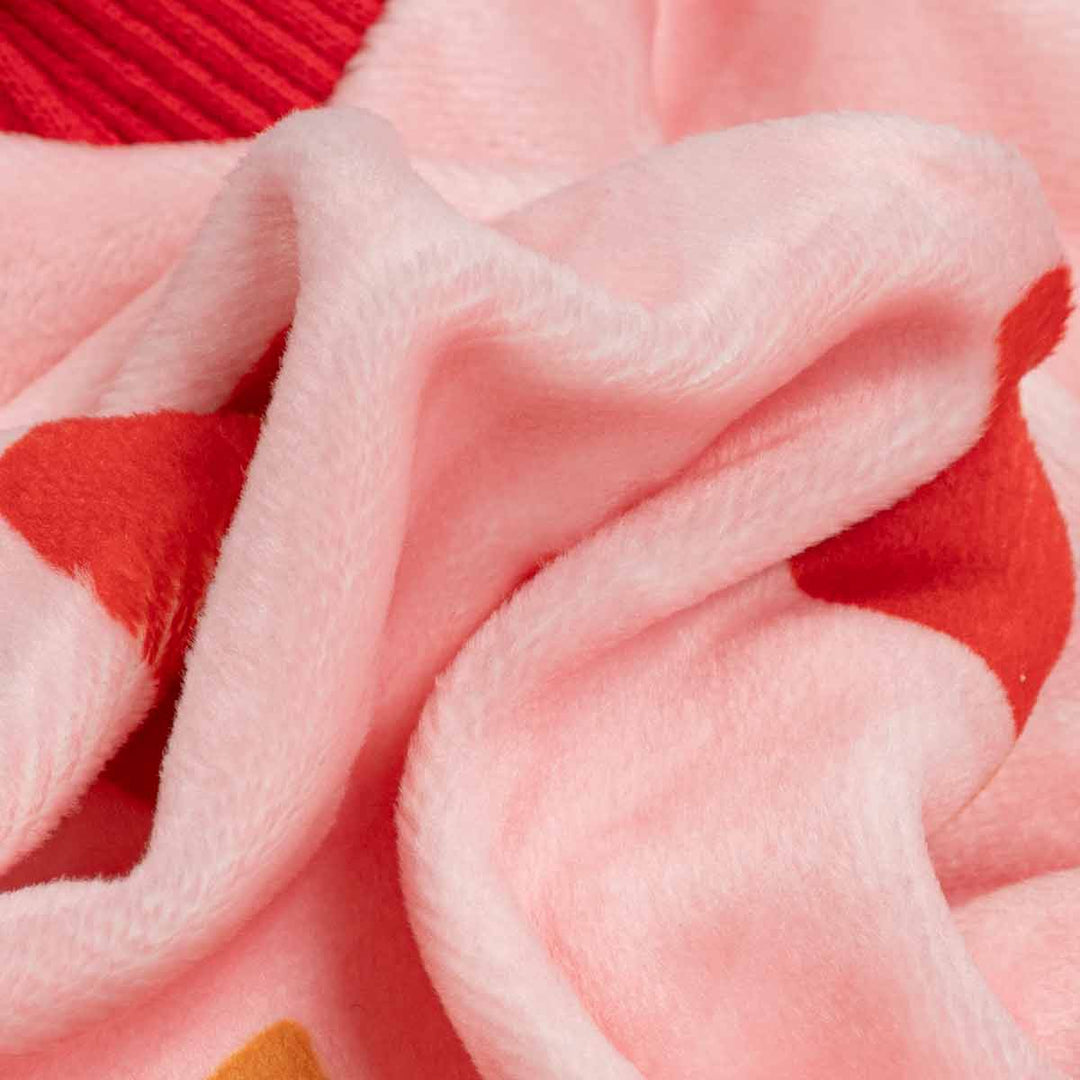 Close-up of a soft plush fabric in light pink with red heart-like shapes and arrow prints, showing the texture and folds of the material