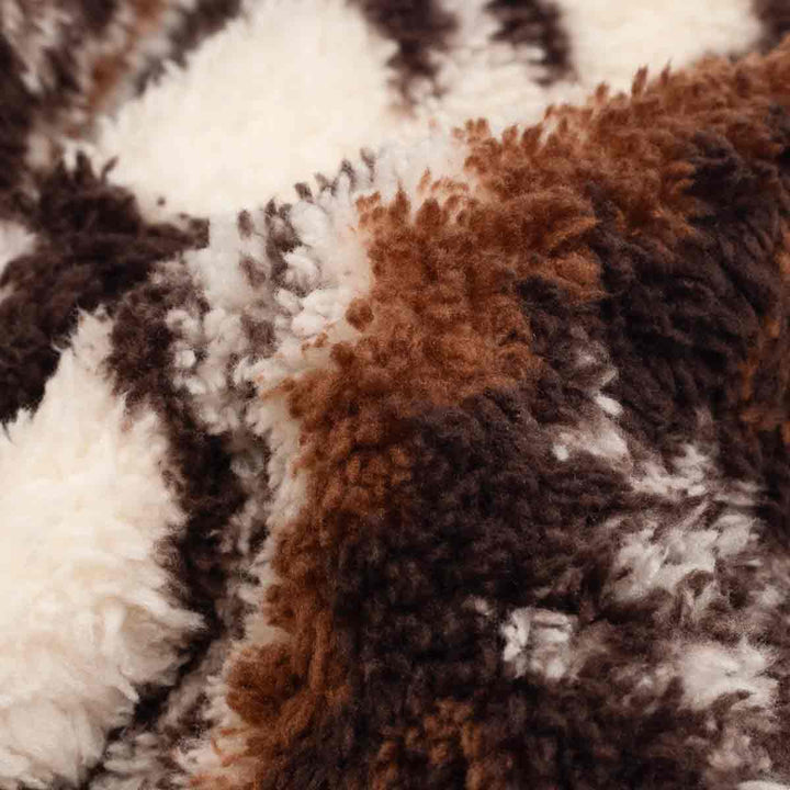Close-up of a fur fabric with a mottled pattern of brown, dark brown, cream, and white