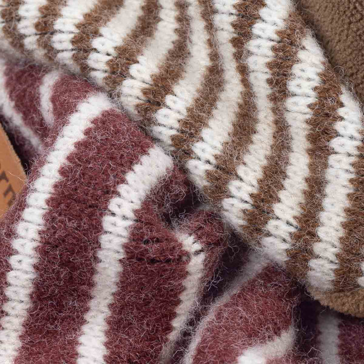 Close-up of a fuzzy knit textile with alternating vertical stripes in brown, cream, and muted burgundy