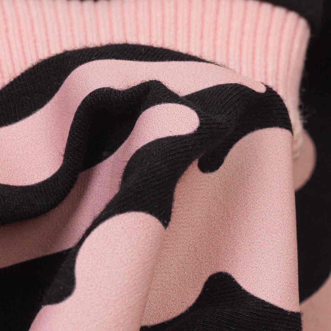 Close-up of a pink knit fabric with a spooky dog skeleton pattern, showing the texture and drape of the material