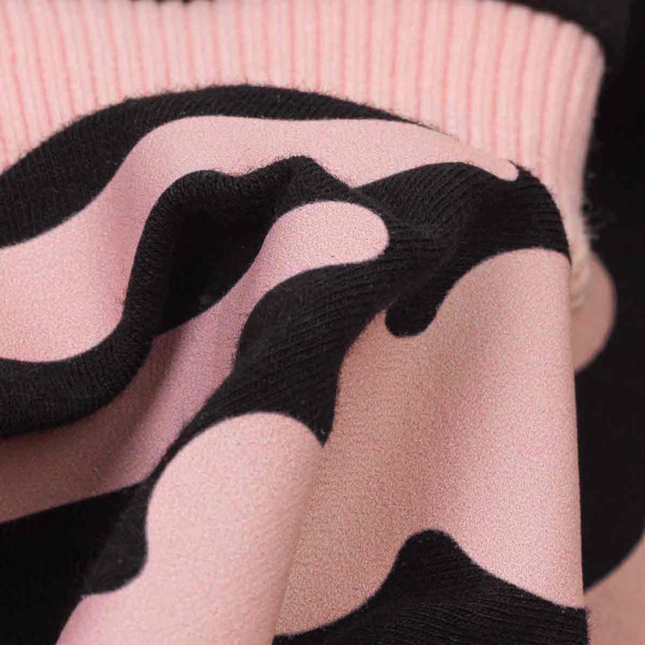 Close-up of a pink knit fabric with a spooky dog skeleton pattern, showing the texture and drape of the material
