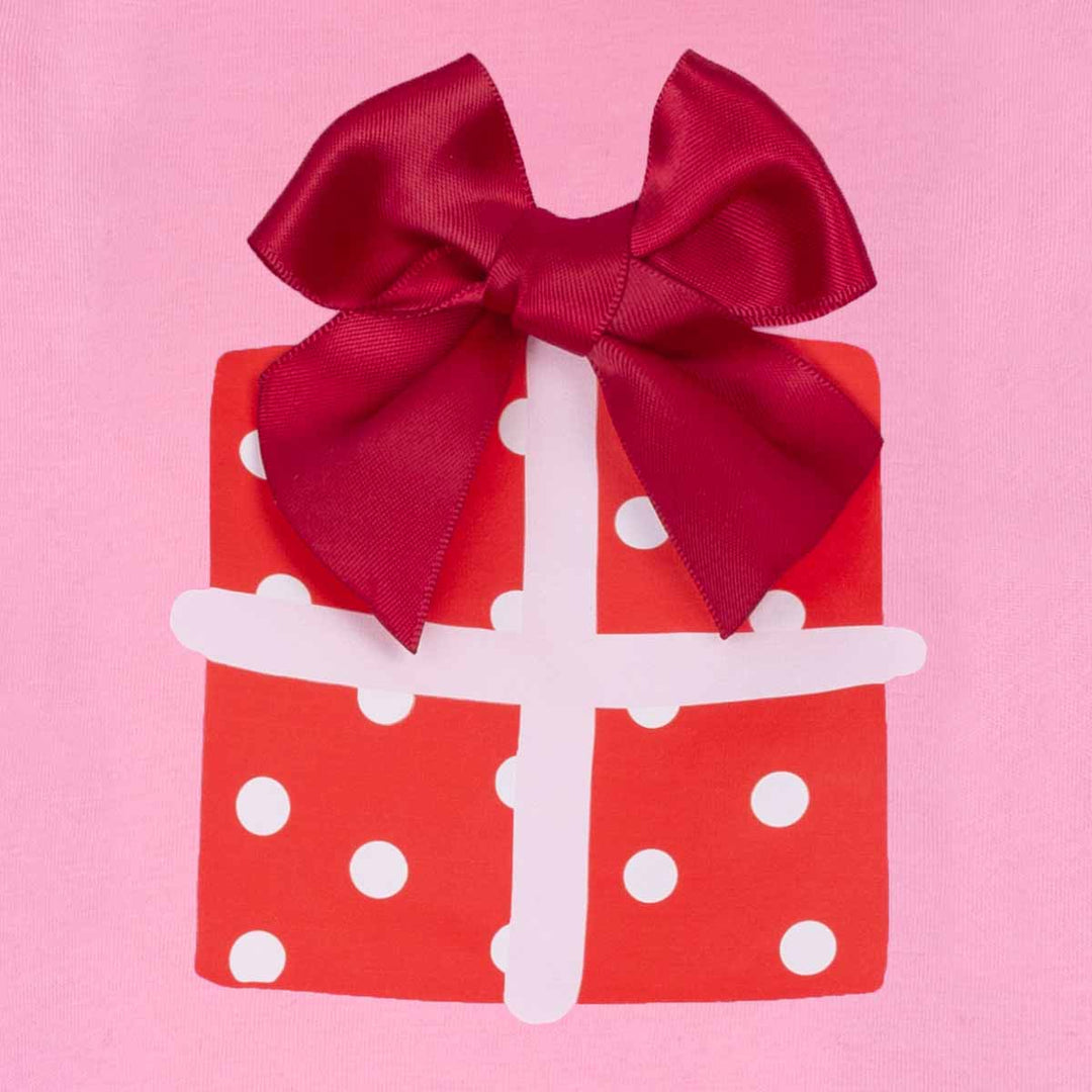 Red gift box with white polka dots and a large red bow on a pink background