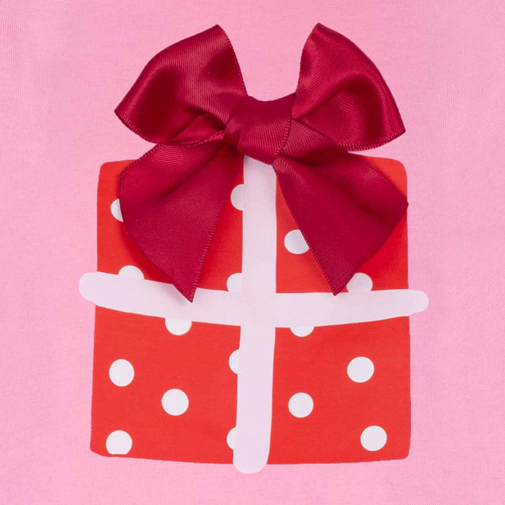 Red gift box with white polka dots and a large red bow on a pink background