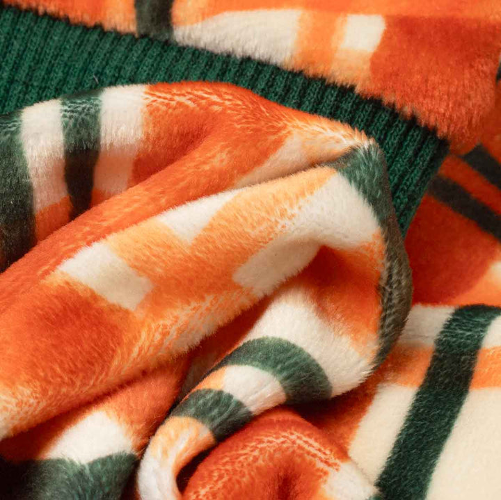 Close-up of a dog fleece pajamas with a striped pattern in orange, white, and dark green, draped to show its soft texture