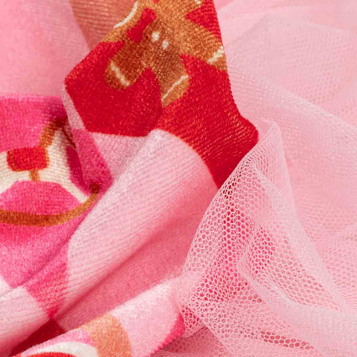 Close-up of a pink scarf featuring a red and gold patterned woven section layered over a sheer, light pink mesh fabric