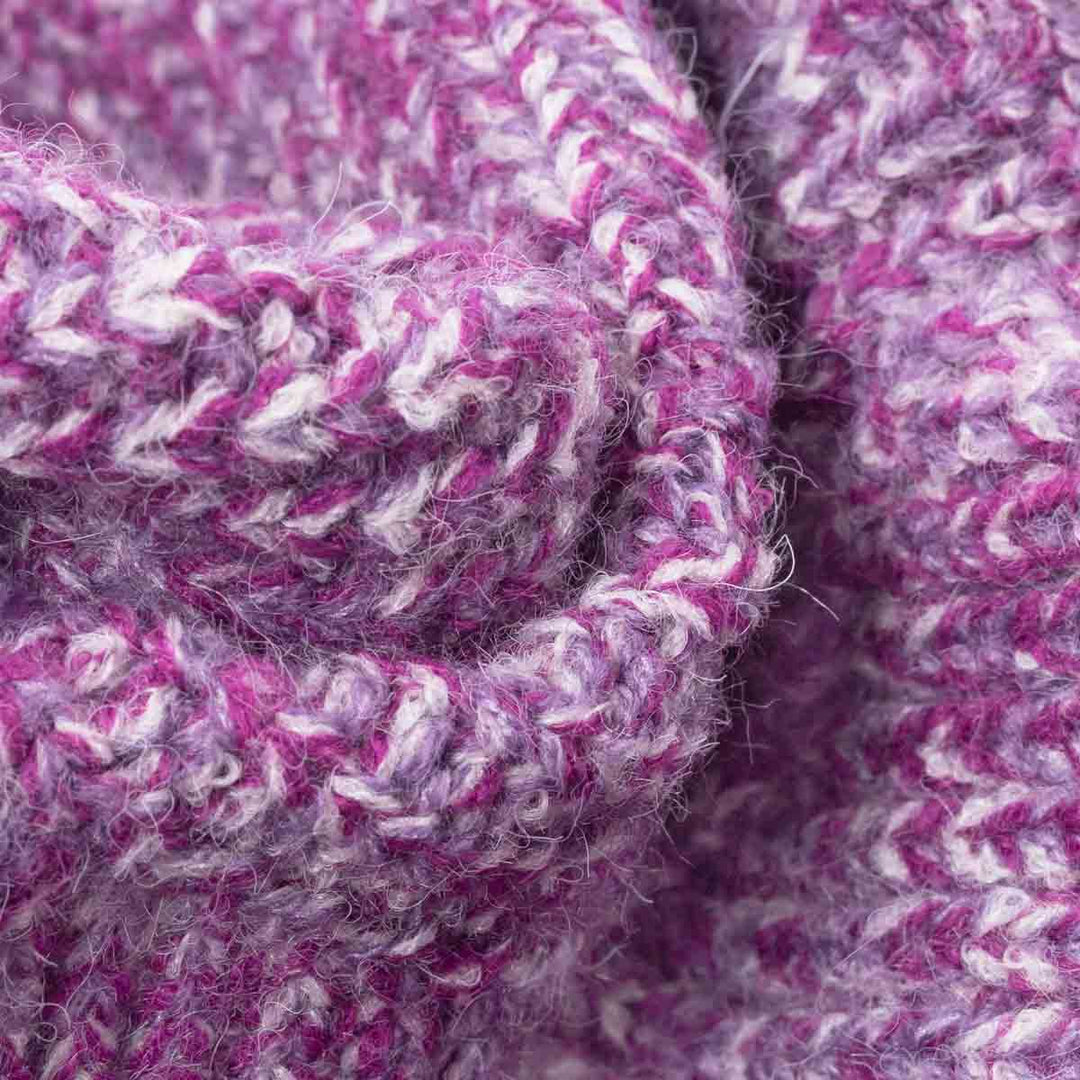 Close-up of a chunky knit fabric with a variegated pattern of purple, magenta, and white yarn