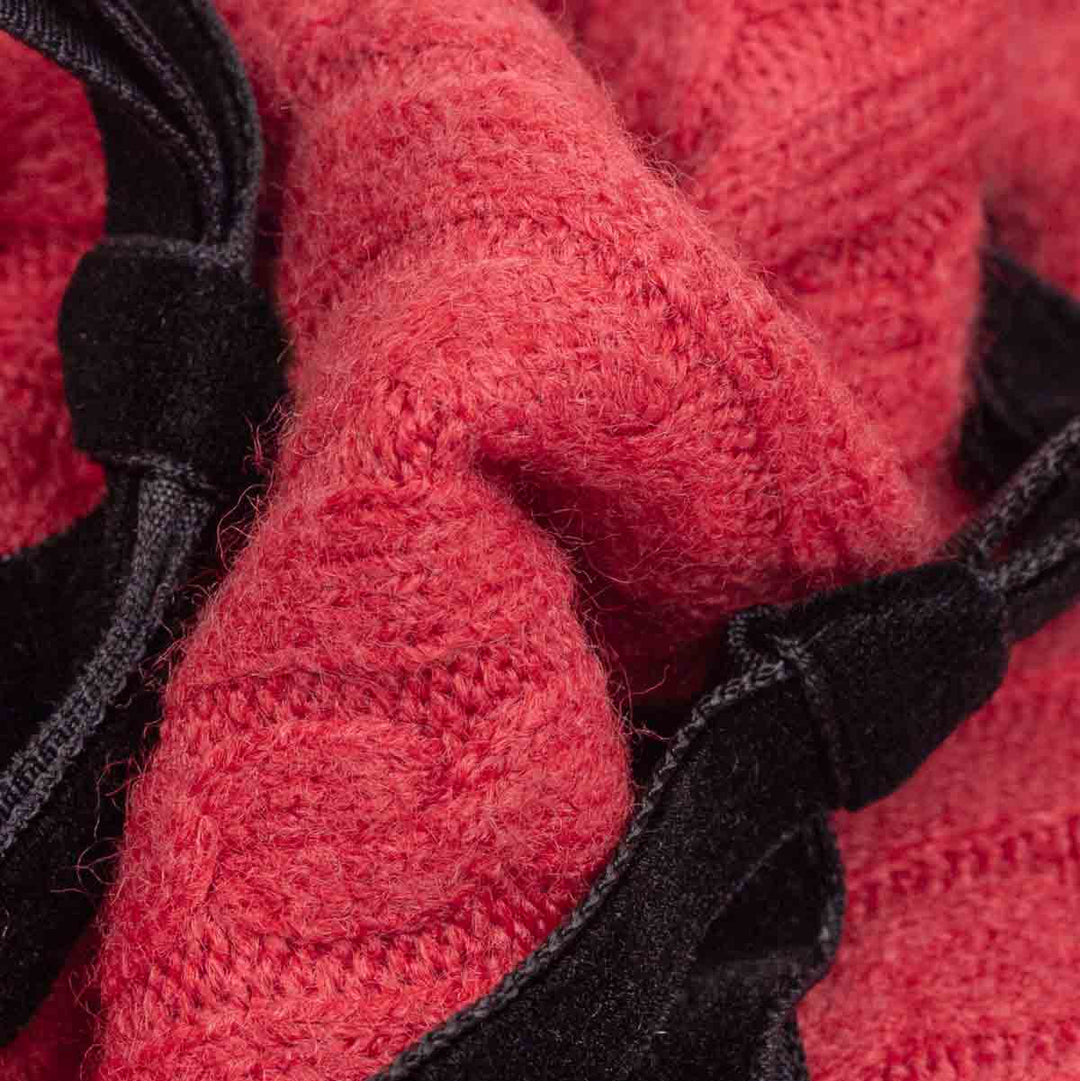 Close-up of a red textured knit fabric with black trim and straps
