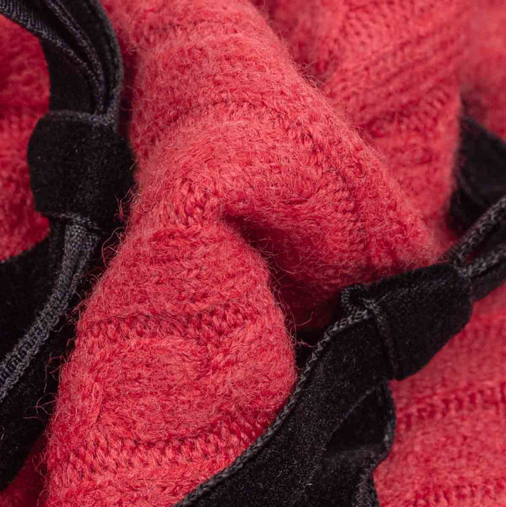 Close-up of a red textured knit fabric with black trim and straps