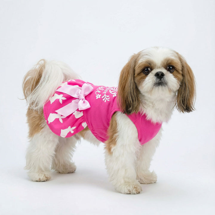 Pink Easter dog dress with bunny print and "Eggstra Cute" text, featuring a satin bow.