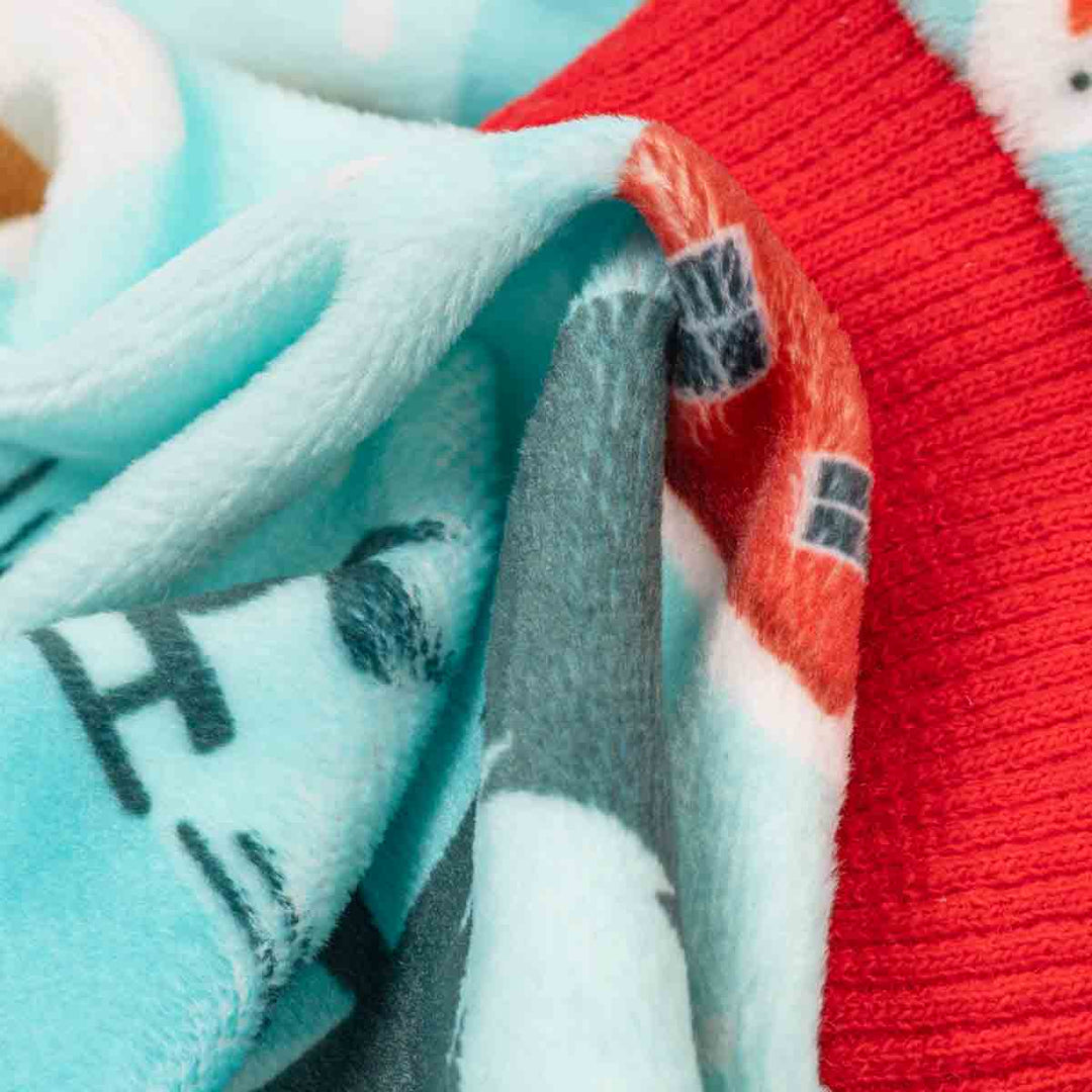 Close-up of a cozy dog onesie with a holiday design, showing light blue, red, gray, and white sections with printed patterns