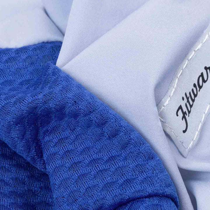 Close-up of a blue textured fabric and a light gray dog onesie with Fitwarm label.