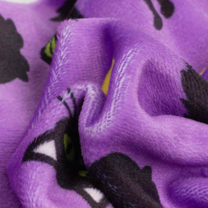 Close-up of a plush purple fabric on dog Halloween pj with a black and white cat and small yellow moon prints