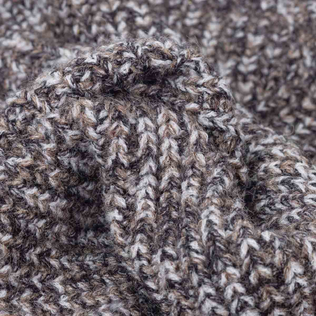 Close-up of a heathered knit fabric with a marled pattern of brown, gray, and off-white yarn, showing the detailed knit texture