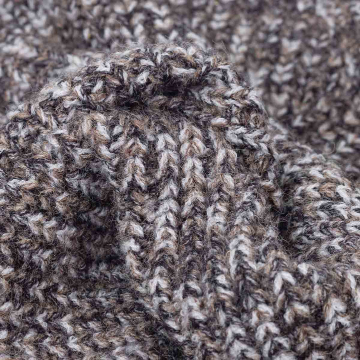 Close-up of a heathered knit fabric with a marled pattern of brown, gray, and off-white yarn, showing the detailed knit texture