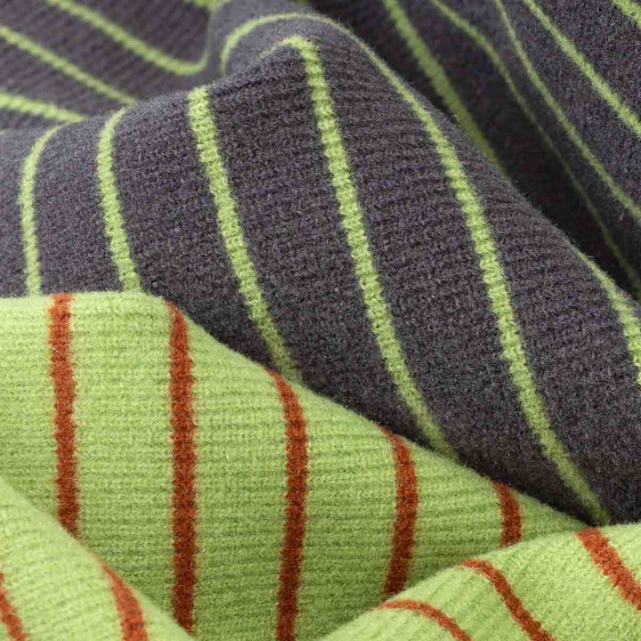 Close-up of striped knit fabric with two sections: dark charcoal gray with lime green stripes, and light lime green with rust red stripes
