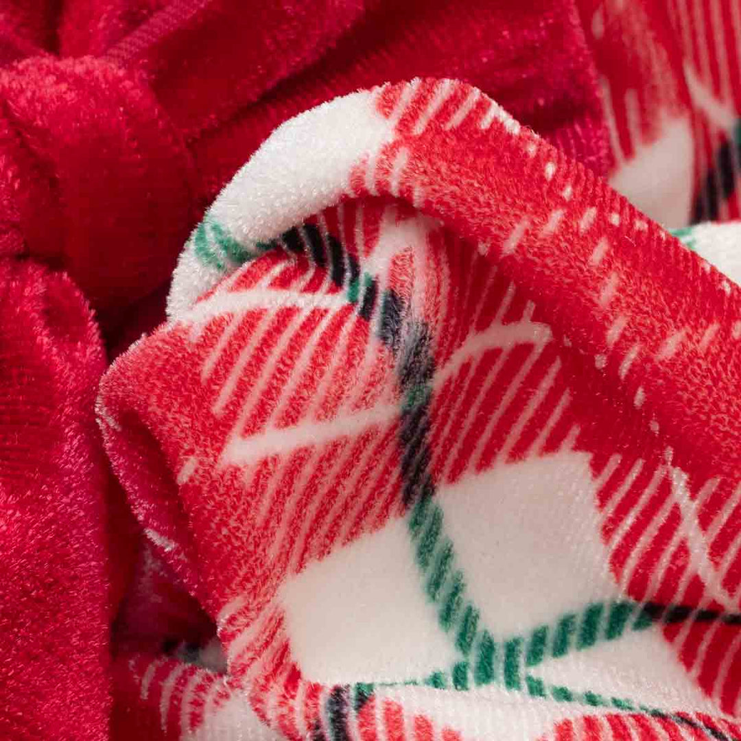 Close-up of a plush fleece dog dress with a red and white plaid pattern and green accents