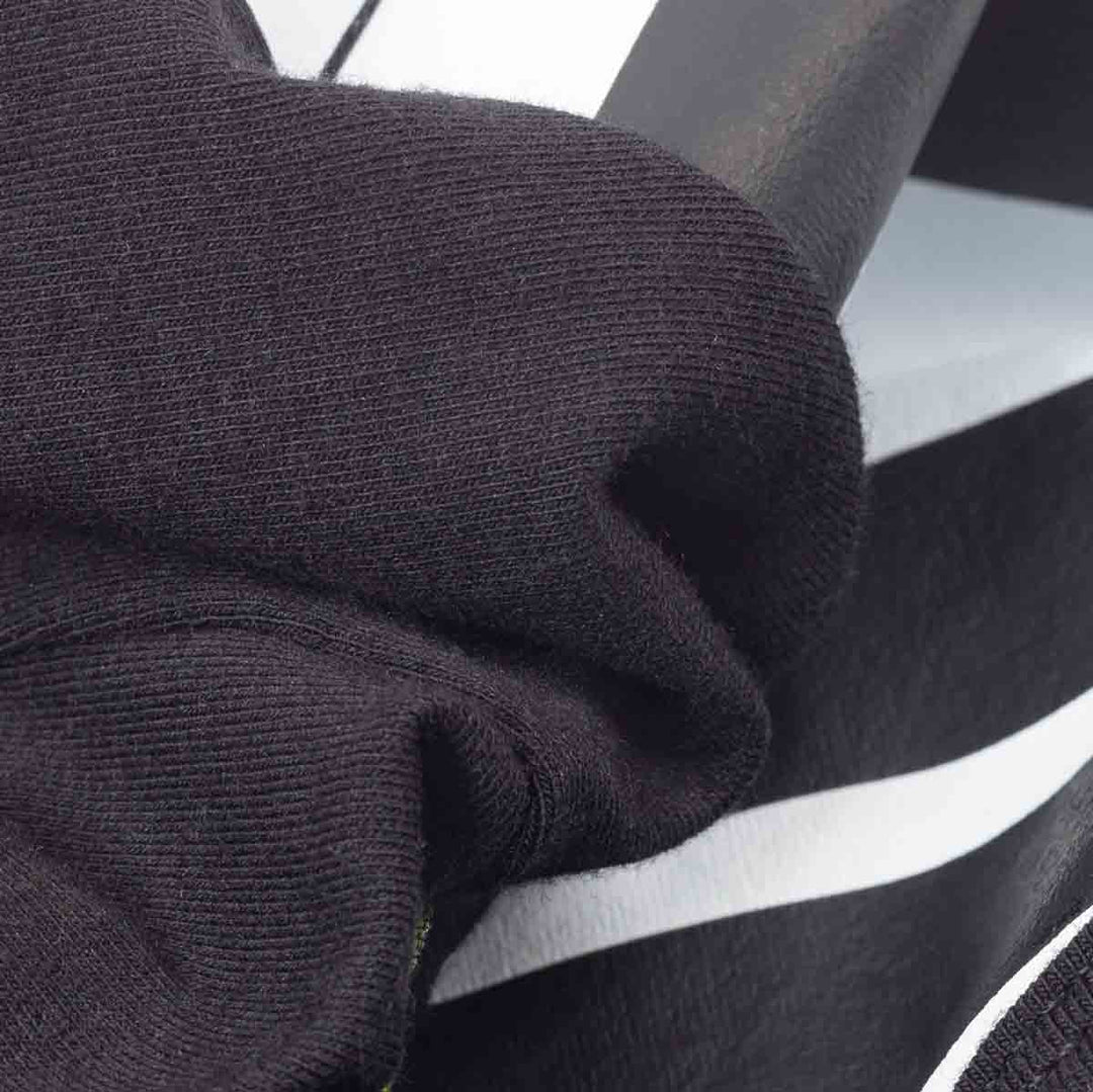 Close-up of a black ribbed knit fabric of dog costume draped over a black and white piano keyboard, showing texture and material detail