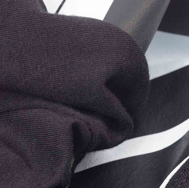 Close-up of a black ribbed knit fabric of dog costume draped over a black and white piano keyboard, showing texture and material detail