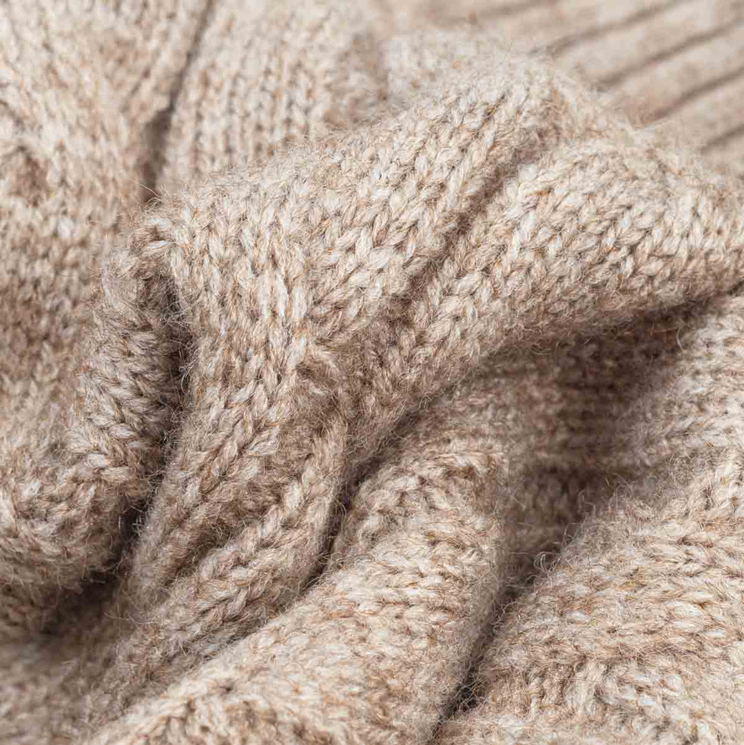 Close-up of a soft, chunky knit fabric in a warm  beige color, showing the detailed texture of the yarn and stitches