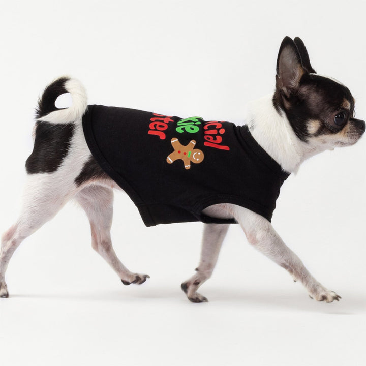 Cute dog dressed in festive black Christmas dog tank top featuring gingerbread cookie and holiday lettering.