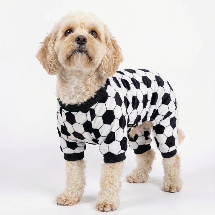 Curly-haired dog standing in soccer dog pajamas with full-leg coverage and classic black-and-white ball pattern
