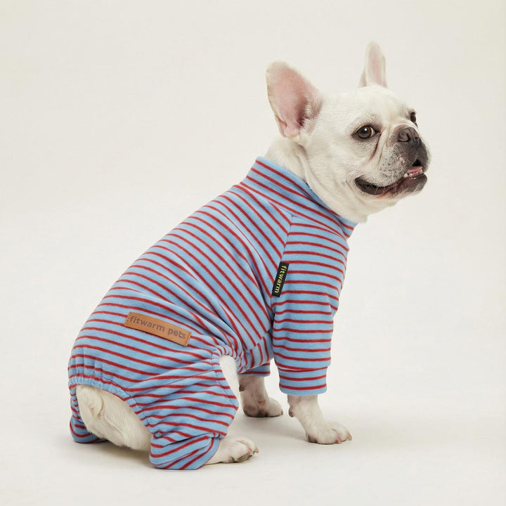French bulldog sits in a blue-and-red striped full-body dog pjs against a clean white background