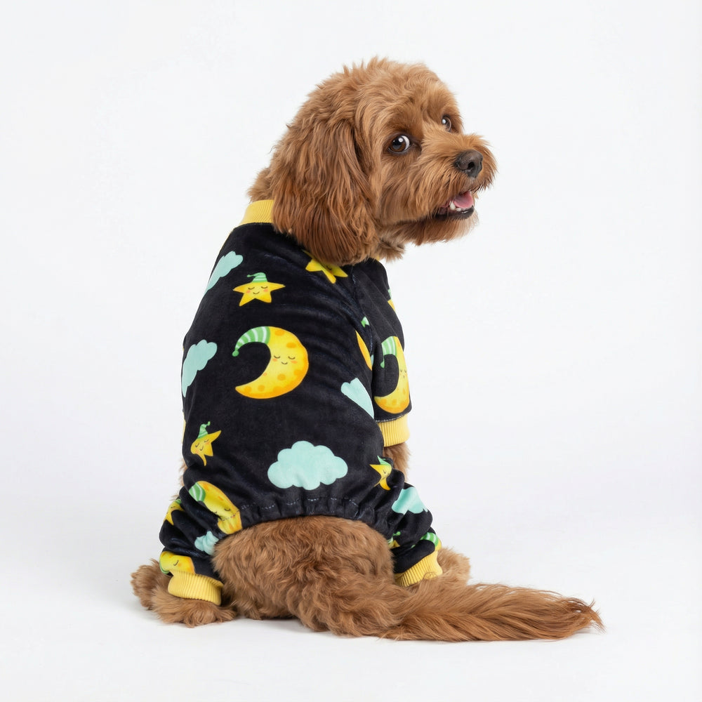 Cute brown dog in cozy black dog pajamas featuring yellow moons, stars, and clouds.