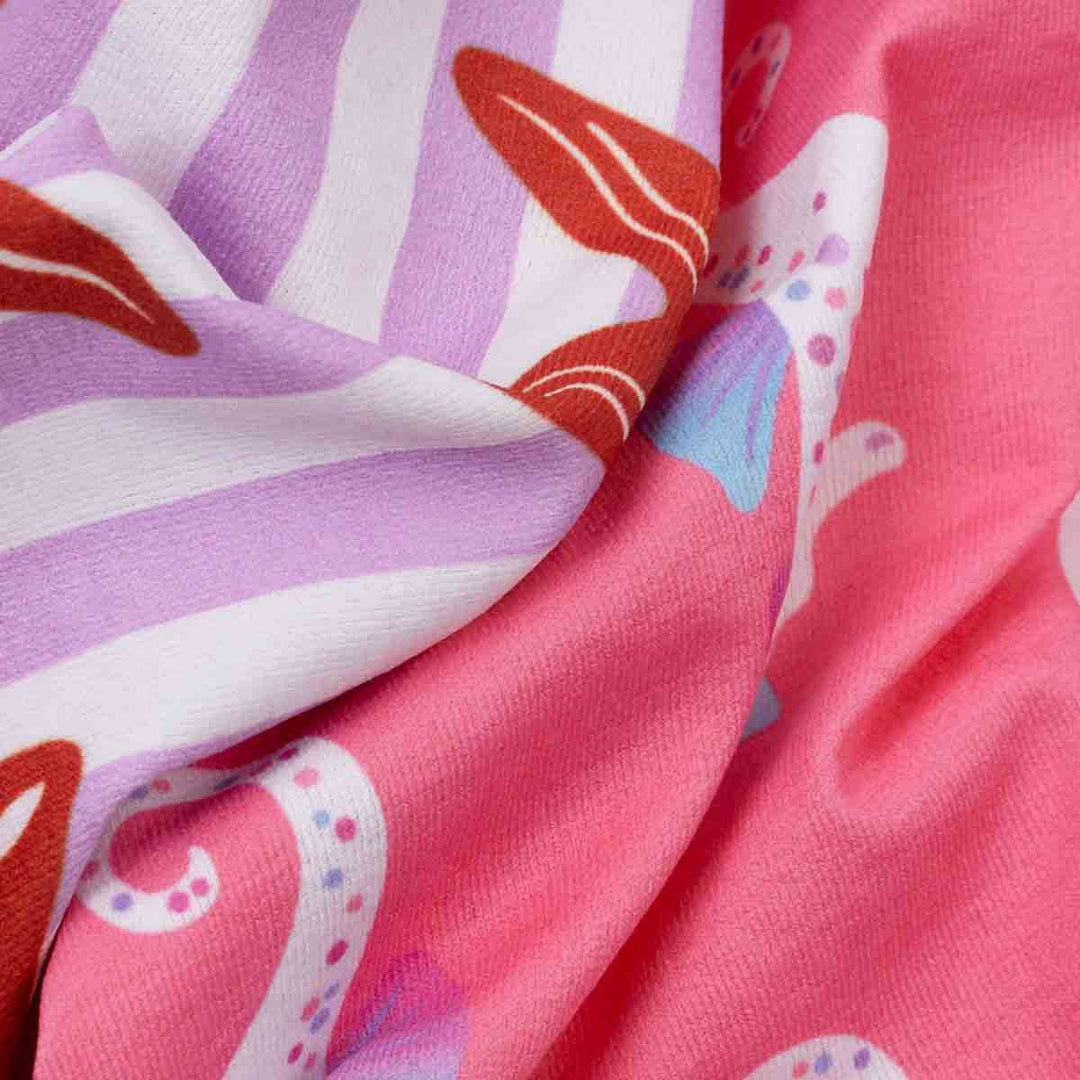 Close-up of fabric with colorful seahorse and starfish pattern on a pink and purple background