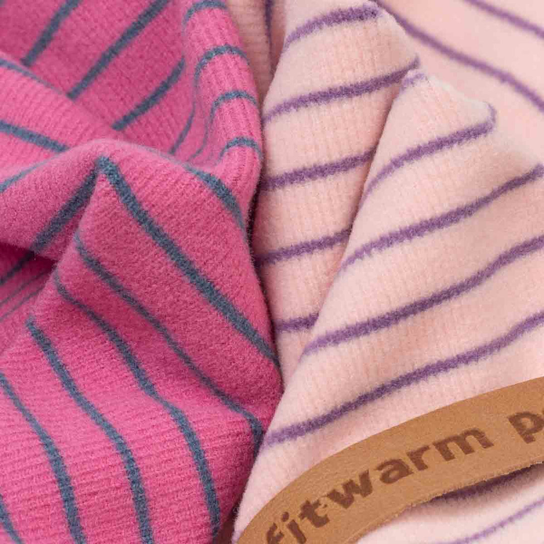 Close-up of two soft striped knit fabrics of dog pajamas, one in pink with teal stripes and one in pale pink with purple stripes