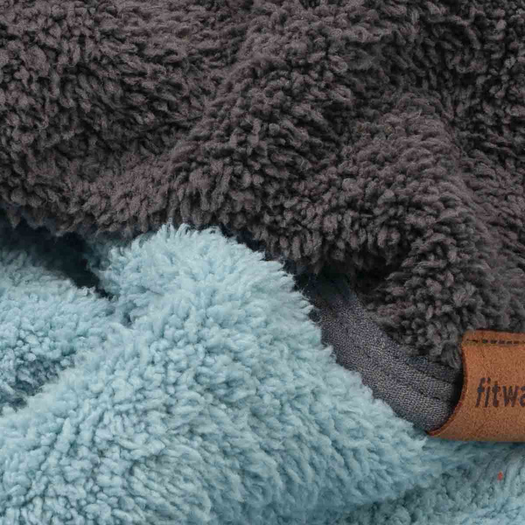 Close-up of fleece fabric in two colors: a dark charcoal gray and a light icy blue, with a small brown leather brand tab