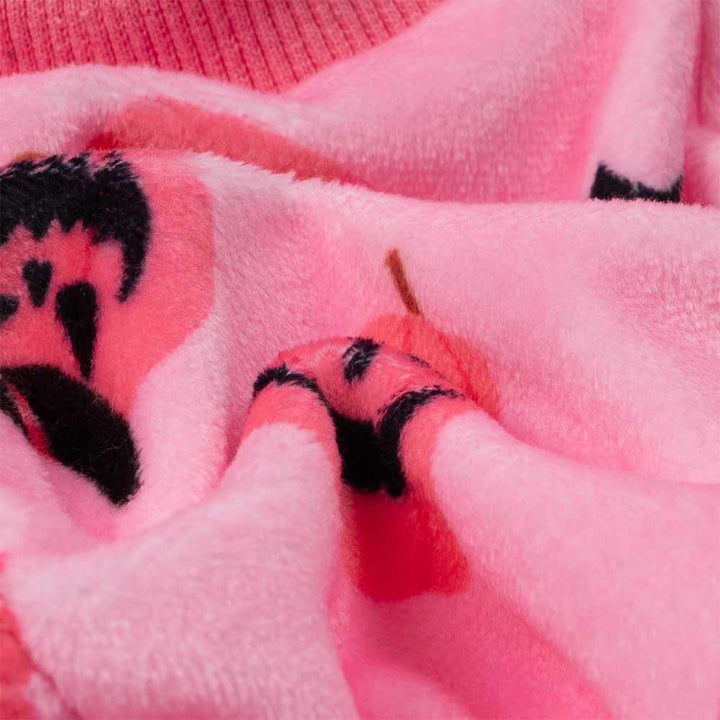 Close-up of soft pink dog pajamas fabric, showing plush polyester, stretchy collar, and Halloween pumpkin patterns.