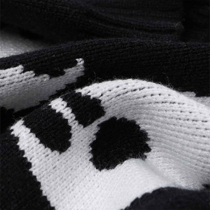 Close-up of soft, stretchy black and white knit fabric, showing detailed spooky ghost patterns for dog sweater.